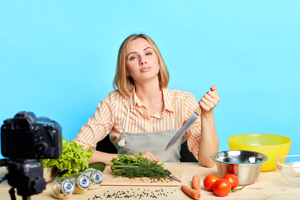Food blogger girl posing with knife in hand, gazing directly in camera - Zdjęcie, obraz