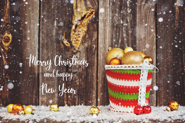 古い茶色の素朴な木製の背景に金の木の装飾ボールとバケツの装飾品のクリスマス構成. - 写真・画像