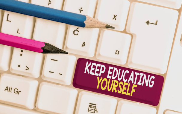 Conceptual hand writing showing Keep Educating Yourself. Business photo text dont stop studying Improve yourself using Courses White pc keyboard with note paper above the white background. - Photo, Image