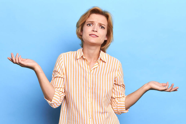 puzzled unhappy young woman shrugging her shoulders - Photo, image