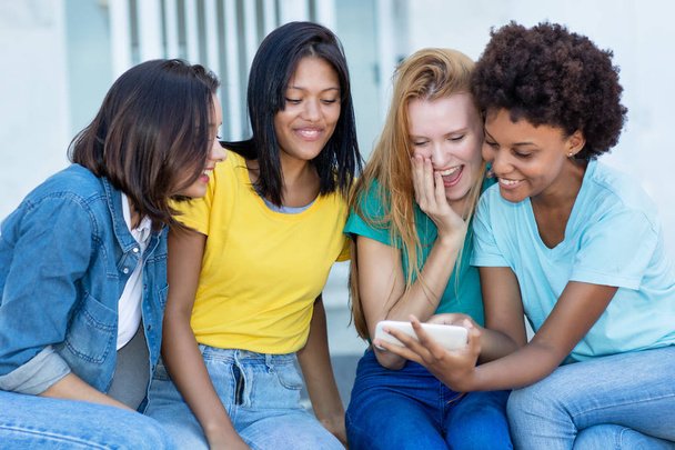 Group of multi ethnic  girls watching movie clip at cellphone - Fotó, kép