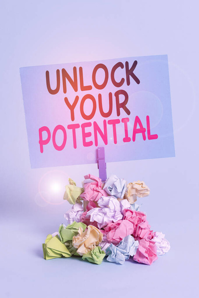 Text sign showing Unlock Your Potential. Conceptual photo improve self awareness Skills to Achieve more Reminder pile colored crumpled paper clothespin reminder blue background. - Photo, Image