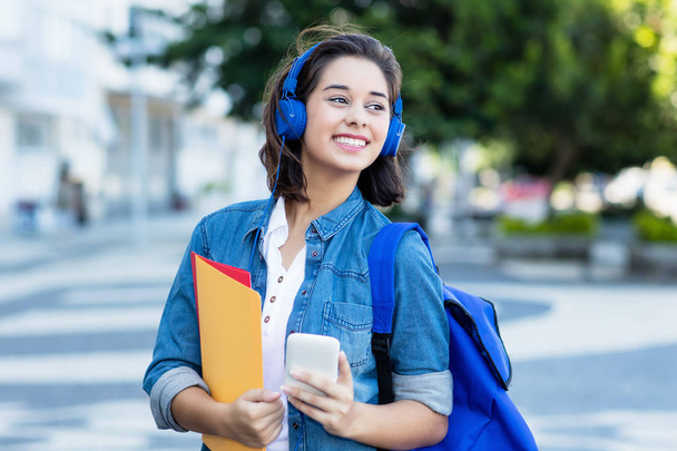 Cute spanish female student with backpack and earphones - Фото, изображение