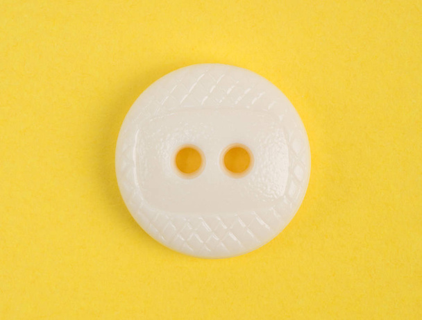 White plastic button on yellow background - Fotoğraf, Görsel