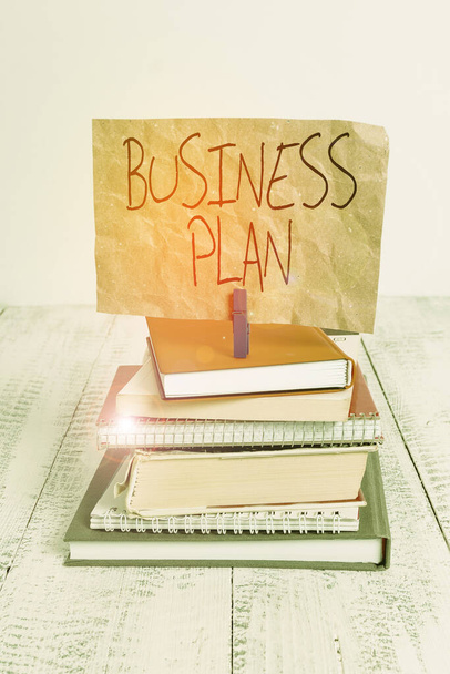 Writing note showing Business Plan. Business photo showcasing Structural Strategy Goals and Objectives Financial Projections pile stacked books notebook pin color reminder white wooden. - Zdjęcie, obraz