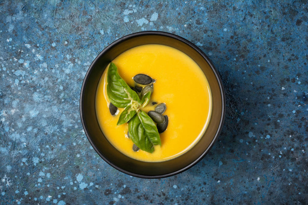 Bowl of vegetarian pumpkin soup with seeds and basil - Фото, изображение