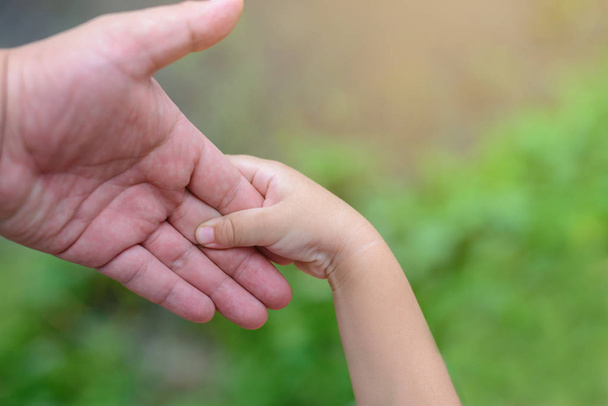 Close-up da mão do pai segurando a mão de seu filho ao ar livre
. - Foto, Imagem
