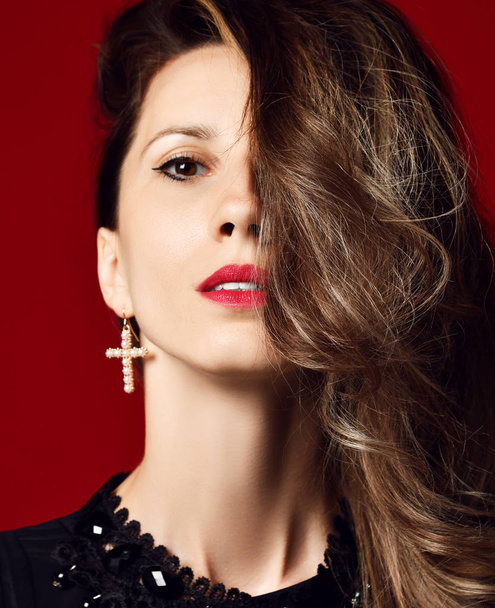 Beautiful woman fashion art studio portrait with windy hair modern earring on red  - Photo, Image