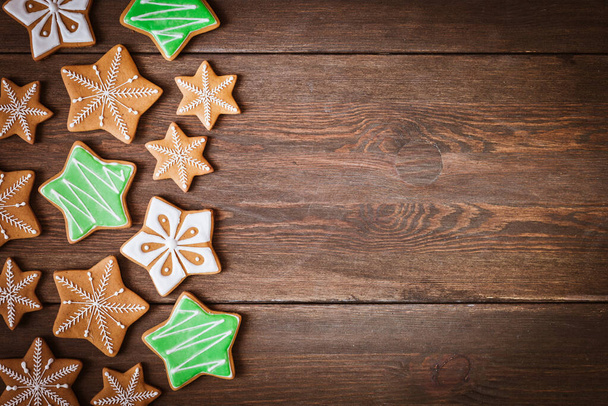 γιορτινά χριστουγεννιάτικα μπισκότα μελόψωμο σε σχήμα αστεριού βρίσκονται σε ξύλινο σκούρο καφέ φόντο. - Φωτογραφία, εικόνα