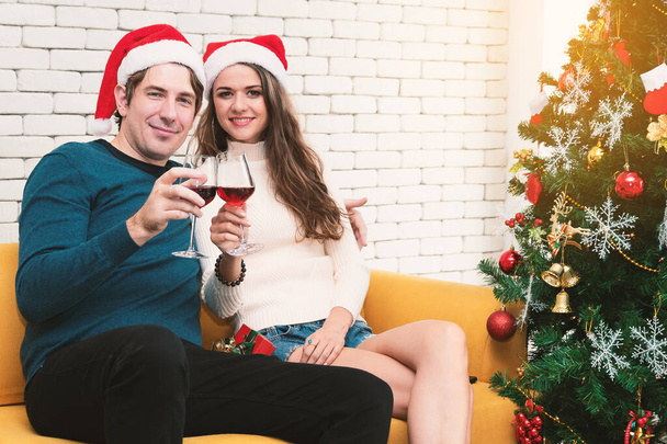 Το ζευγάρι κάθεται πίνοντας κόκκινο κρασί στον καναπέ. - Φωτογραφία, εικόνα