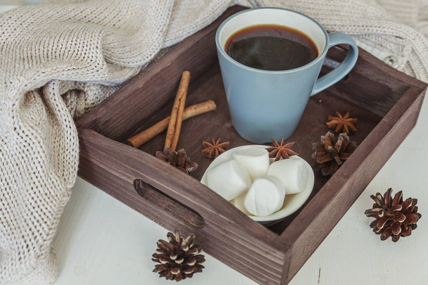 Cup of coffee on rustic wooden tray, sweet marshmallow and warm woolen sweater - Photo, Image