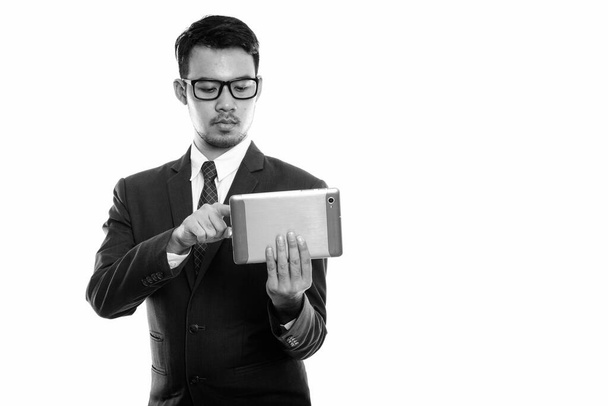 Studio shot of young Asian businessman using digital tablet - Fotó, kép