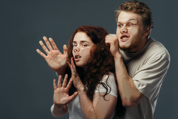 Young couple faces crushed on transparent glass, funny emotion. Man and woman with pressed grimaces standing at the showcase, humor, uncomfortable looking - Foto, imagen