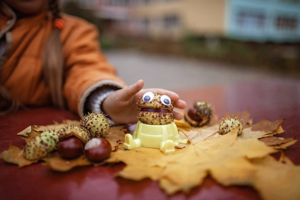 Jesienne liście i kasztan z oczami zabawki na stole  - Zdjęcie, obraz