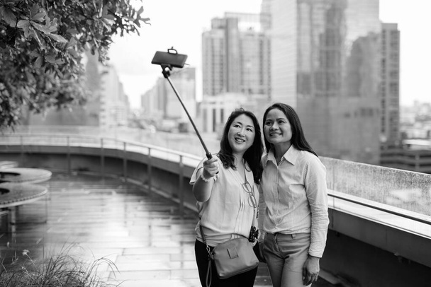 アジアの女性は自撮り棒に付けられた携帯電話を使って自撮り - 写真・画像