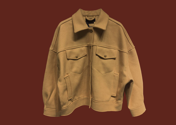 茶色の労働者スタイルのジャケットウールブレンドジャージは、赤の背景に隔離された。ポケット付きのファッショナブルなショートコート。服の構成。フラットレイアウト、トップビュー、コピースペース。冬服のパターン - 写真・画像