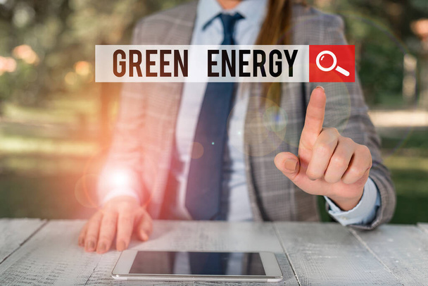 Написання тексту "Зелена енергія". Бізнес-концепція походить від природних джерел і не шкодить екосистемі Жіночий бізнесмен сидить за столом, тримаючи мобільний телефон
. - Фото, зображення