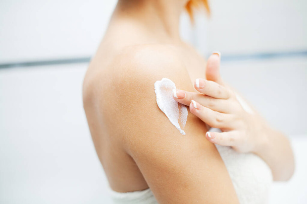 Huidverzorging. Vrouw gebruik huidverzorgingsproducten thuis in lichte badkamer - Foto, afbeelding