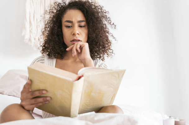 Concentrated international woman reading interesting love story - Фото, зображення