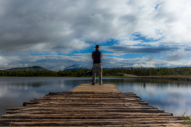 Auto-retrato de caminhante em um cais em um lago norueguês
 - Foto, Imagem