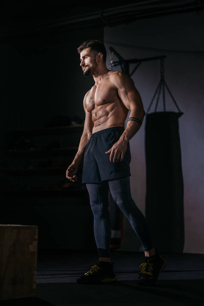 Carrosserie portrait d'homme debout devant la caméra et posant dans un cours de gym avec fond noir
 - Photo, image