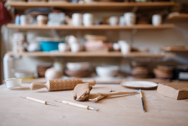 Plottery equipment on wooden table in workshop, nobody. Handmade clay tableware molding and shaping, traditional hobby, utensils making - Photo, Image