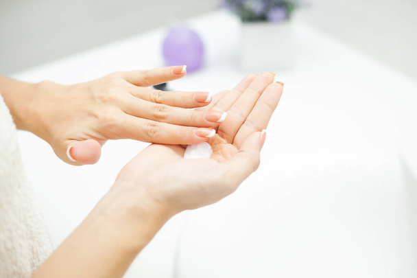 Ihonhoito. Nainen käyttää ihonhoitotuotteita kotona valossa kylpyhuoneessa
 - Valokuva, kuva