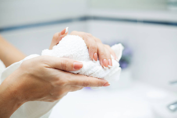 Hygiëne en handverzorging. Vrouw met behulp van handdoek voor het afvegen van handen droog na het wassen in lichte badkamer thuis - Foto, afbeelding