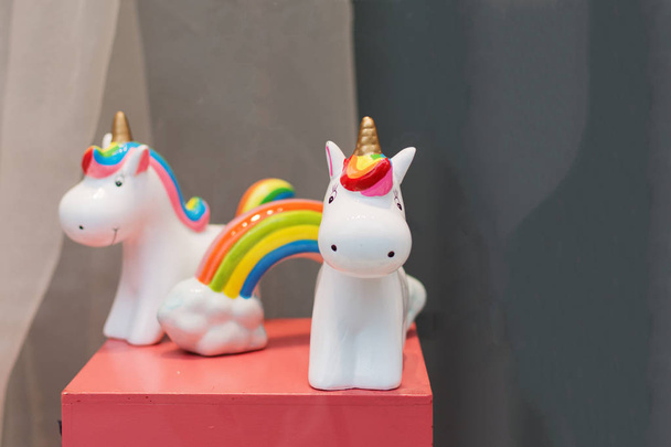 Caja de dinero de juguete unicornio de recuerdo de cerámica con arco iris colorido en la mesa rosa
. - Foto, Imagen