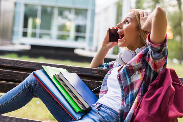 Female student in panic using phone while studying outdoor. - Foto, imagen