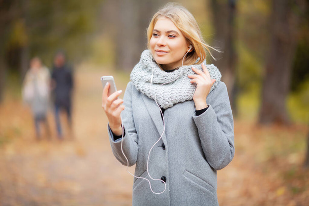 Young Beauty woman listening music in autumn forest - Foto, Imagen
