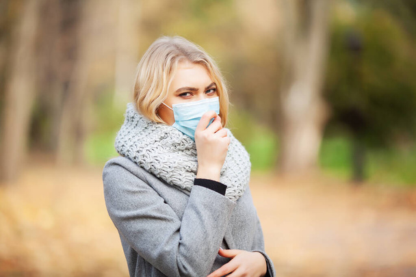 Zima a chřipka. Žena s maskou lékařské tváře v přírodě v podzimním lese - Fotografie, Obrázek