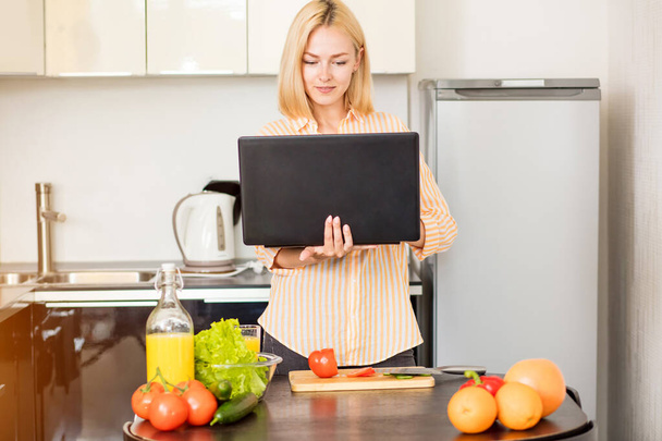 Woman using laptop in the kitchen - Valokuva, kuva