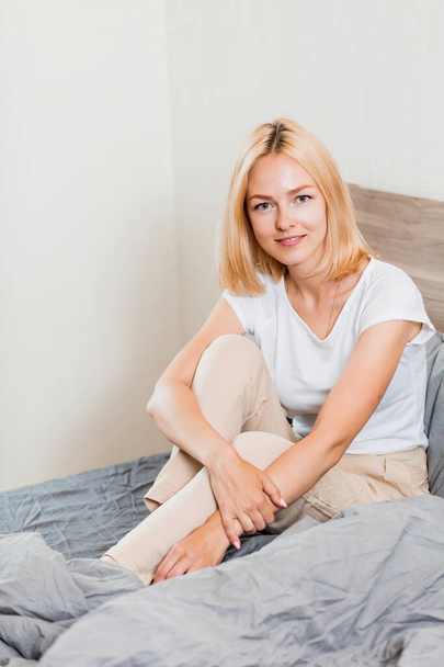 Positive woman sitting in bed at home - Фото, изображение