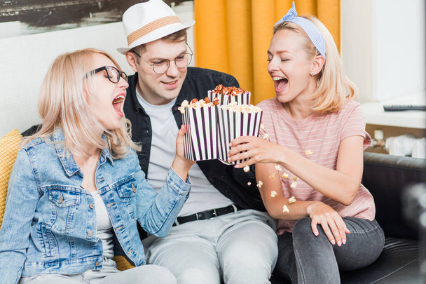 Cheerful group of friends eating popcorn at home - Foto, Imagem