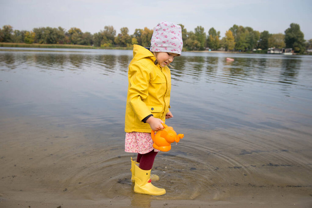 Ευτυχισμένο κορίτσι με κίτρινο αδιάβροχο και μπότες  - Φωτογραφία, εικόνα