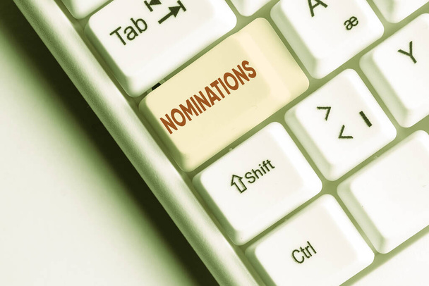 Conceptual hand writing showing Nominations. Business photo text the act of officially suggesting someone for a job or position White pc keyboard with note paper above the white background. - Photo, Image