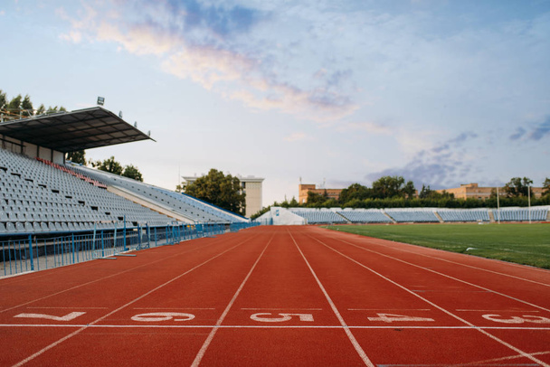 Start line for running on stadium, nobody, front view. Empty treadmill with numbers, injury-proof coating, jogging surface on sport arena - Photo, Image