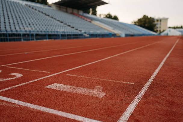 Стартова лінія для бігу на стадіоні, ніхто, вид спереду. Порожня бігова доріжка з номерами, травматичне покриття, бігова поверхня на спортивній арені
 - Фото, зображення