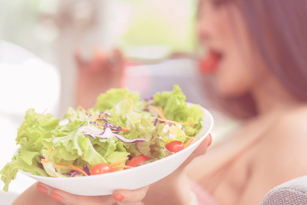 Mulher está comendo salada de legumes saudável verde e relaxante em ho
 - Foto, Imagem