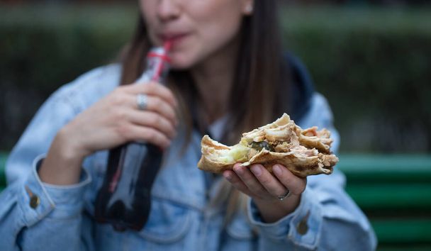 Mladá žena jíst rychlé občerstvení na ulici. - Fotografie, Obrázek
