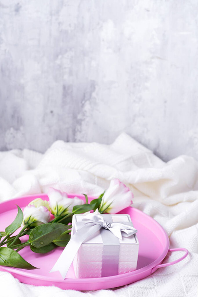 Gift box and pastel flowers eustoma for Valentines or Mothers day on pink tray on bed . Flat lay style. - Photo, Image