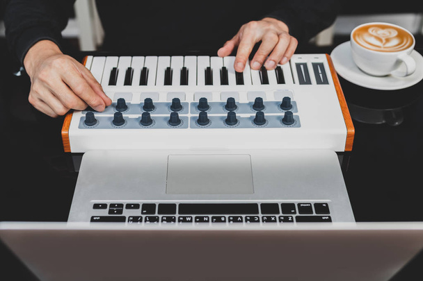 producteur de musique masculin arrangeant et mixant une chanson sur clavier midi et ordinateur portable dans un café
 - Photo, image