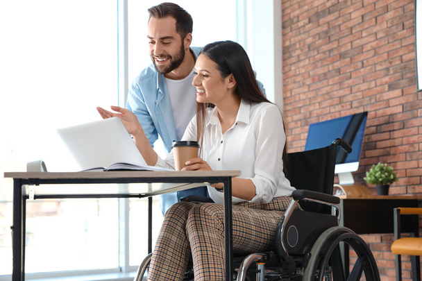 Young woman in wheelchair with colleague at workplace - Foto, Imagem