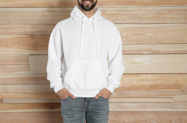 Young man in sweater at wooden wall, closeup. Mock up for design - Foto, afbeelding