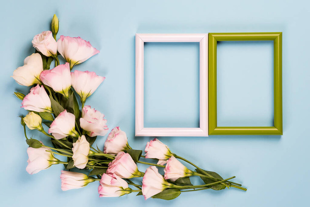 Empty color frames and flowers eustoma on blue paper background with copy space. Flat lay. Love concept - Photo, Image