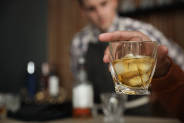Young man with glass of whiskey in bar, closeup. Space for text - Foto, afbeelding