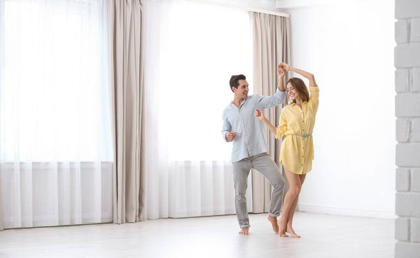 Beautiful young couple dancing in room at home - 写真・画像