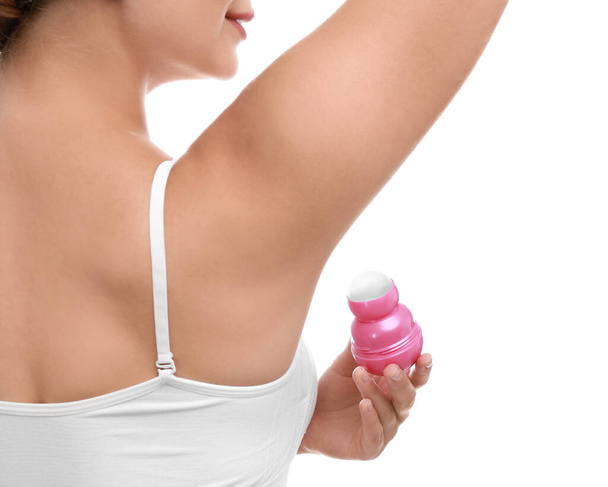 Jeune femme appliquant déodorant aux aisselles sur fond blanc, gros plan
 - Photo, image