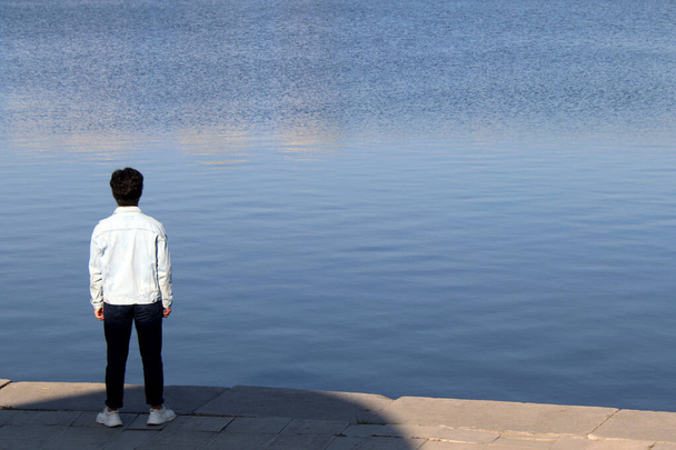 young man stands on the embankment of the city pond - Fotografie, Obrázek